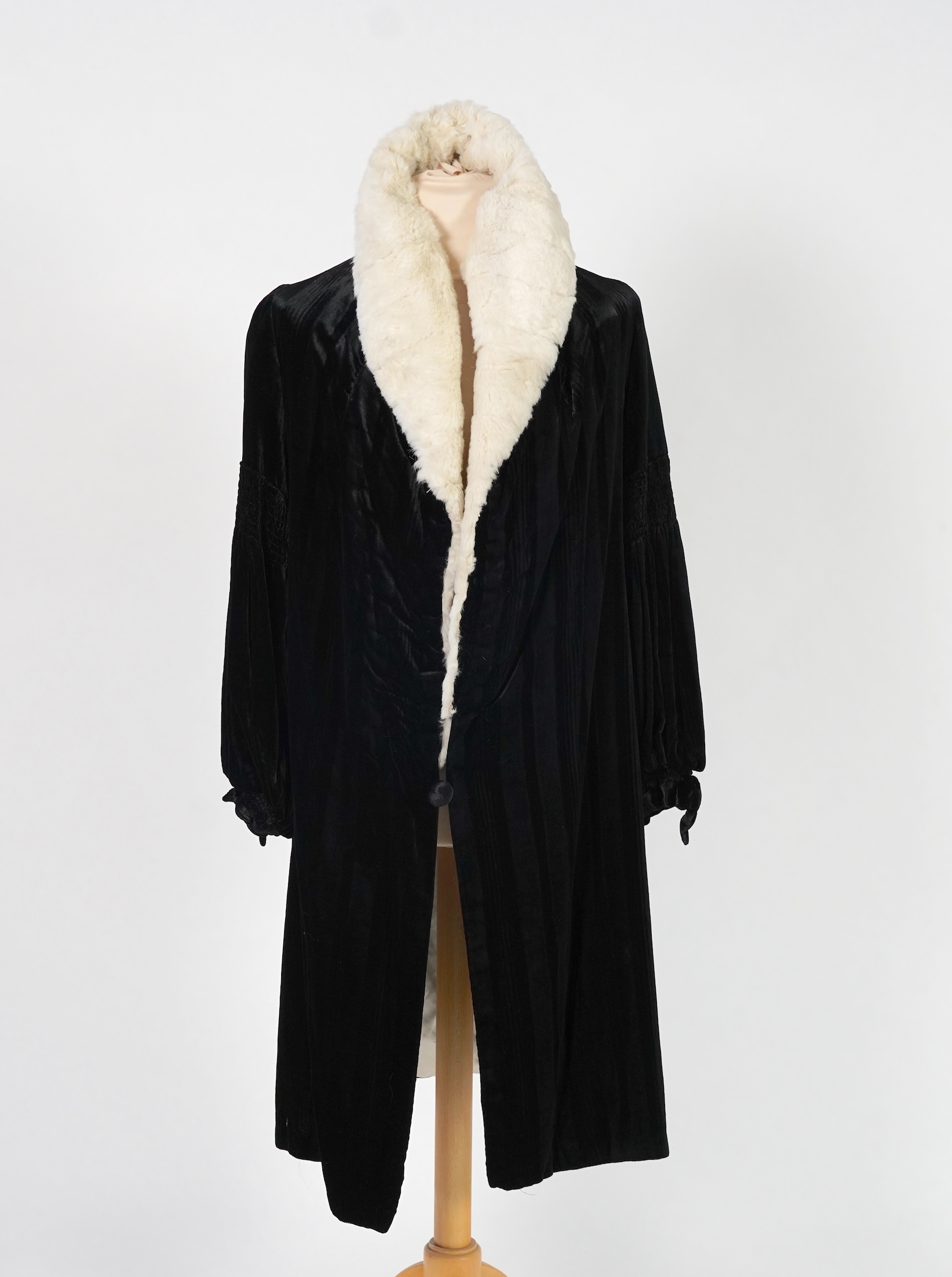 A 1920's ladies black striped silk velvet opera coat with a wide white fur collar and cream satin lining.